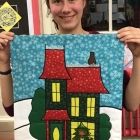 Emma Hill proudly displays her finished Christmas wall hanging in Region 14